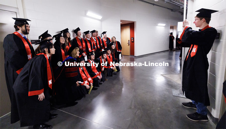 Engineering graduate Zachary Thompson photographs a group of College of Business graduates posing with Dean Kathy Farrell. Winter Undergraduate Commencement in Pinnacle Bank Arena. December 17, 2022. Photo by Craig Chandler / University Communication.