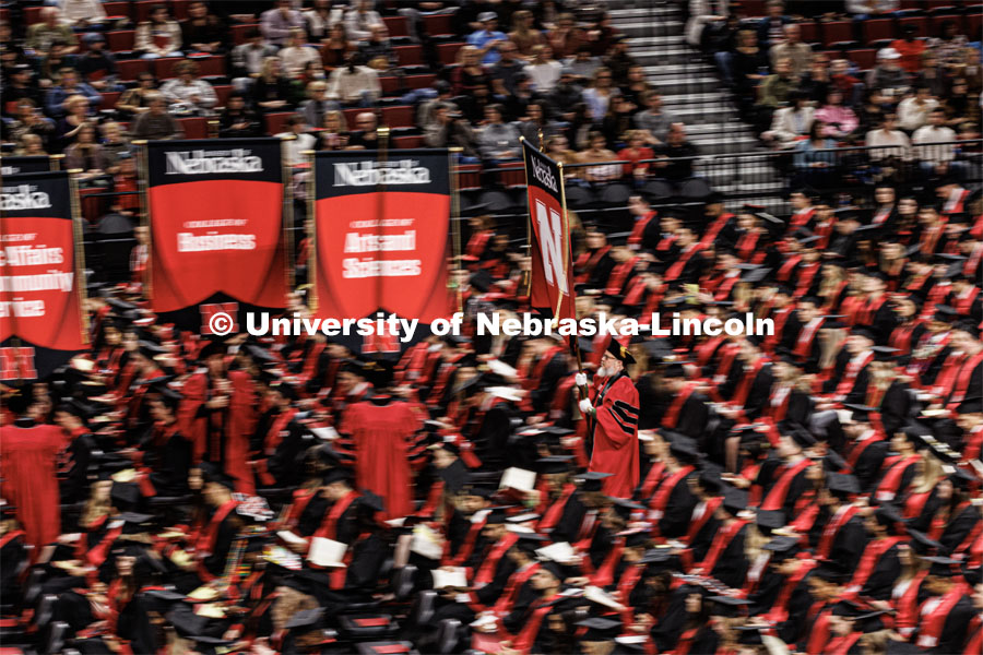 The university gonfalon precedes the platform party through the graduates seated in the arena. Winter Undergraduate Commencement in Pinnacle Bank Arena. December 17, 2022. Photo by Craig Chandler / University Communication.