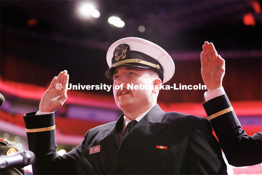Navy Ensign Cohan Bonow and ROTC graduate repeats the oath of office at the beginning of commencement.  Winter Undergraduate Commencement in Pinnacle Bank Arena. December 17, 2022. Photo by Craig Chandler / University Communication.