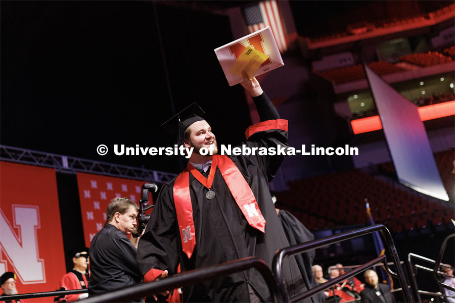 Jacob Muff, a graduate in Emerging Media Arts, waves to family and friends after receiving his diploma. Winter Undergraduate Commencement in Pinnacle Bank Arena. December 17, 2022. Photo by Craig Chandler / University Communication.