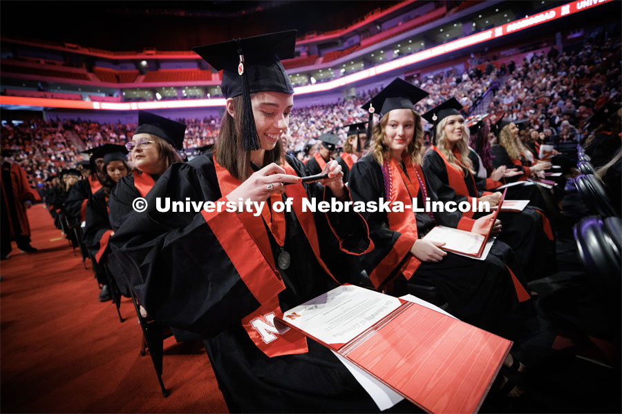 Hannah Jumper photographs her diploma to post to social media after walking across stage. Winter Undergraduate Commencement in Pinnacle Bank Arena. December 17, 2022. Photo by Craig Chandler / University Communication.