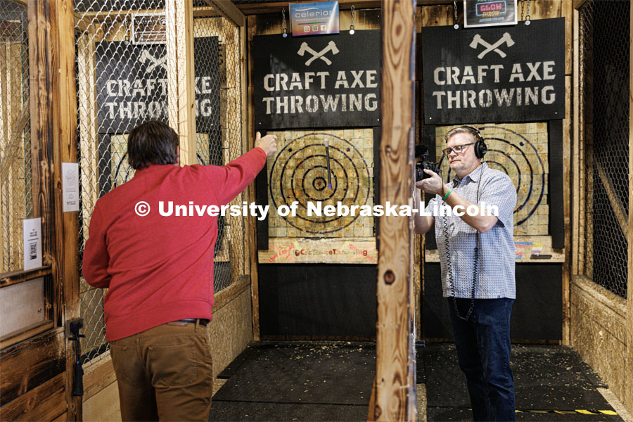 William Thomas, Associate Dean for Research and Graduate Education at the College of Arts and Sciences throws an axe at Craft Axe Throwing while Curt Bright of UCOMM records the moment. January 26, 2023. Photo by Craig Chandler / University Communication.