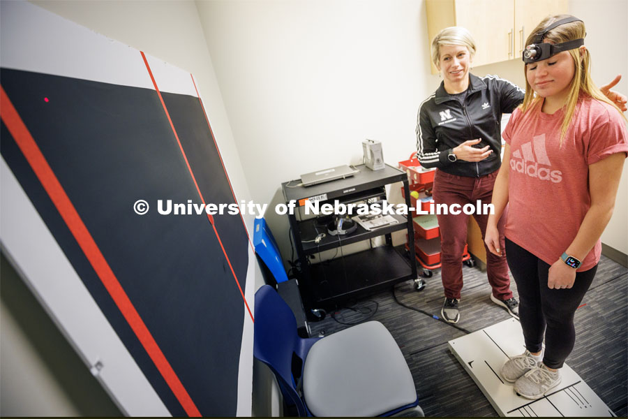 Dr. Kate Higgins, an Athletic Neuropsychologist with Husker Athletics, performs a mCOBALT test (a concussion balance test) on mock patient Makayla Burchett, a freshman from Harlan, Iowa. Burchett wears a laser pointer as she moves her head around a target on the wall while balanced on a force plate. The University Health Center and Nebraska Medicine recently moved its concussion clinic to the Nebraska Performance Lab in the east stadium space. February 1, 2023. Photo by Craig Chandler / University Communication.