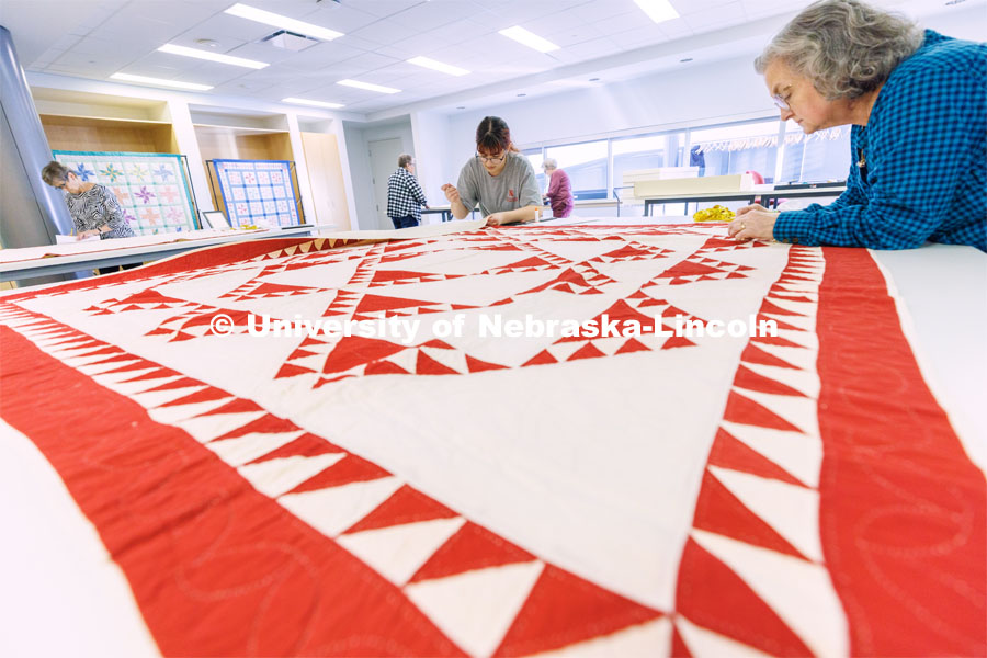 Inas Hskan, a sophomore in Textiles, Merchandizing and Fashion Design and quilt center student worker, sews an identification tag onto the back of a quilt as volunteer Jan Rice inspects the quilt’s stitching. The quilt was made in the United States c. 1880-1920 and is from the Joanna S. Rose Collection. Quilt Center. February 8, 2023. Photo by Craig Chandler / University Communication.