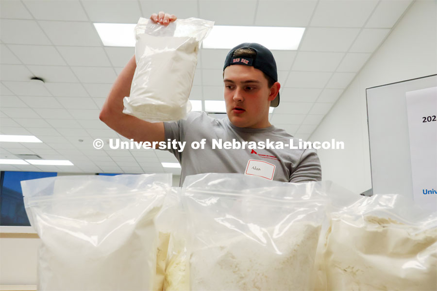 Adam Lierz grabs a package of flour from the ingredient selections during the Battle of the Food Scientists. Groups prepared baked goods using flour made from crickets. Battle of the Food Scientists at Nebraska Innovation Campus. February 15, 2023. Photo by Blaney Dreifurst / University Communication.