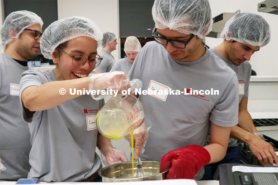 Carmen Perez-Donado pours egg into a mixture as David Fabian Gomez Quintero stirs during the Battle of the Food Scientists. Groups prepared baked goods using flour made from crickets. Battle of the Food Scientists at Nebraska Innovation Campus. February 15, 2023. Photo by Blaney Dreifurst / University Communication.