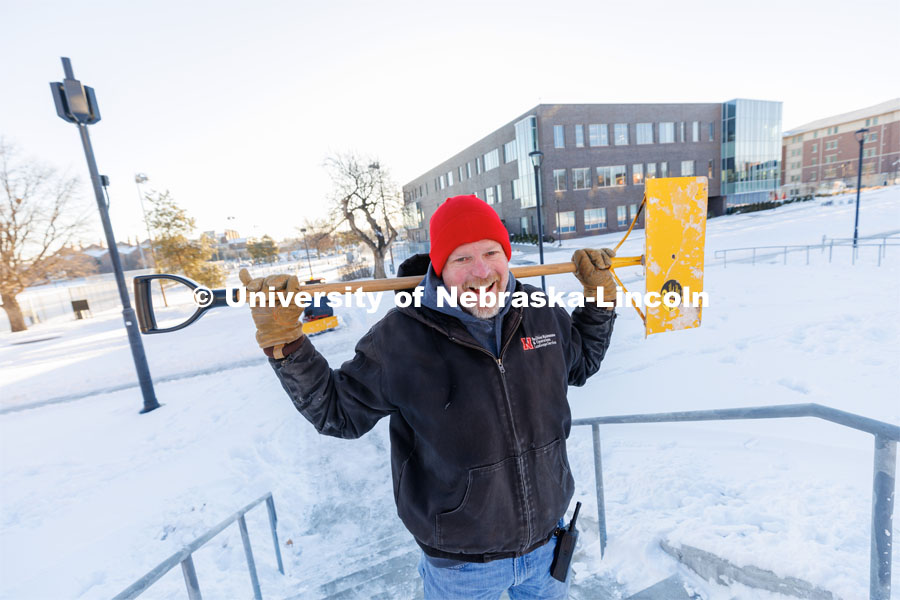 Kevin Rhodes, Area Leader with Landscape Services, pauses from clearing snow on the steps between Cather Dining Center and Niehardt to smile for a photo.  February 17, 2023. Photo by Craig Chandler / University Communication. 