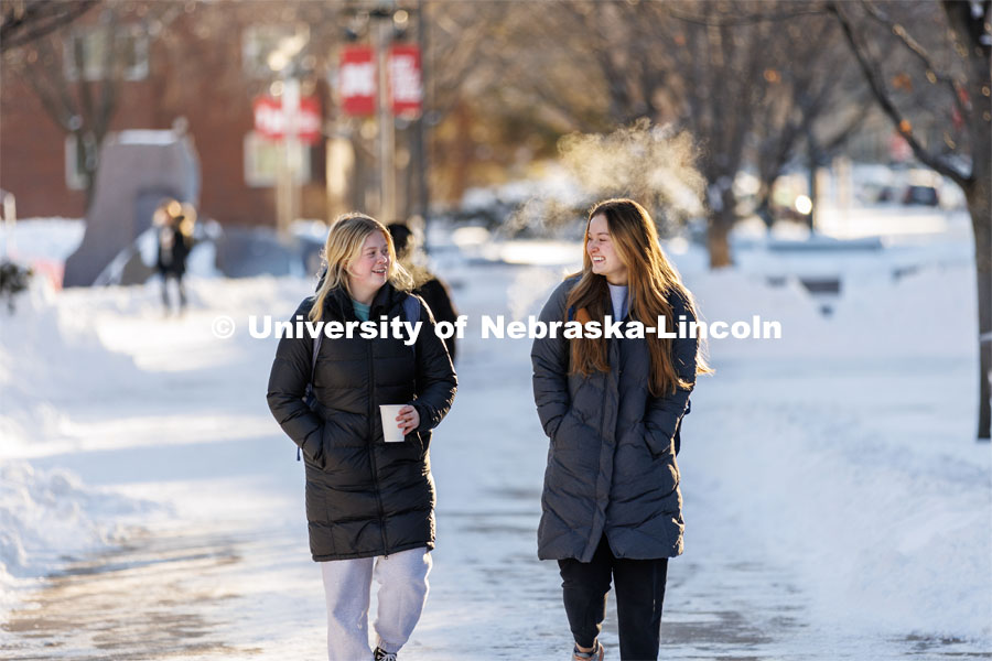 Malia Bloemker, left, and Isabella Shaddick talk as they walk to an early morning class Friday. A snowy Friday on city campus. February 17, 2023. Photo by Craig Chandler / University Communication.