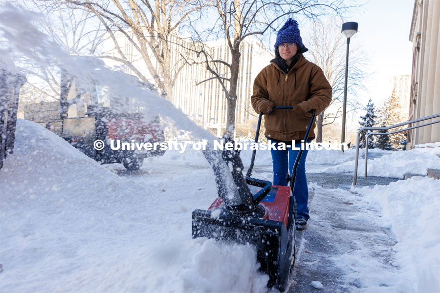 Jessica Roberts, a landscape assistant with Landscape Services, snow blows the sidewalk outside Pound Hall. A snowy Friday on city campus. February 17, 2023. Photo by Craig Chandler / University Communication.