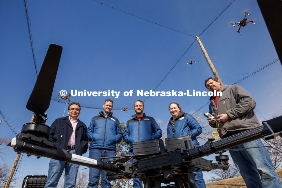(From left) Francisco Muñoz-Arriola, Justin Bradley, Carrick Detweiler, Brittany Duncan and Trenton Franz pose among unmanned aerial vehicles at the NIMBUS outdoor flying area on Nebraska Innovation Campus. The teams have earned two grants to push the boundaries of what robots can do and expand human understanding of how climate change is impacting agricultural, aquatic and wildland systems. March 2, 2023. Photo by Craig Chandler / University Communication.