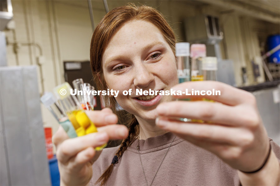 Ryann Freel holds multiple tubes of water samples turned bright colors from chemicals used to measure water quality (pH, ammonia, nitrites, nitrates). Aquatic Biodiversity and Conservation (ABC) Lab. March 27, 2023. Photo by Craig Chandler / University Communication.