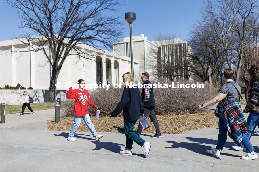 A campus guide walks a set of students and family through campus near the Sheldon Memorial Art Gallery. April 4, 2023. Photo by Craig Chandler / University Communication.