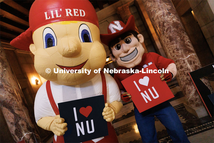 Lil Red and Herbie Husker hold up signs at the I Love NU advocacy event at the Nebraska State Capitol. April 5, 2023. Photo by Craig Chandler / University Communication.