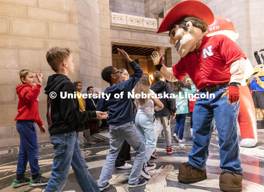 Herbie Husker greats elementary school students on a tour of the capitol during the I Love NU advocacy event at the Nebraska State Capitol. April 5, 2023. Photo by Craig Chandler / University Communication.