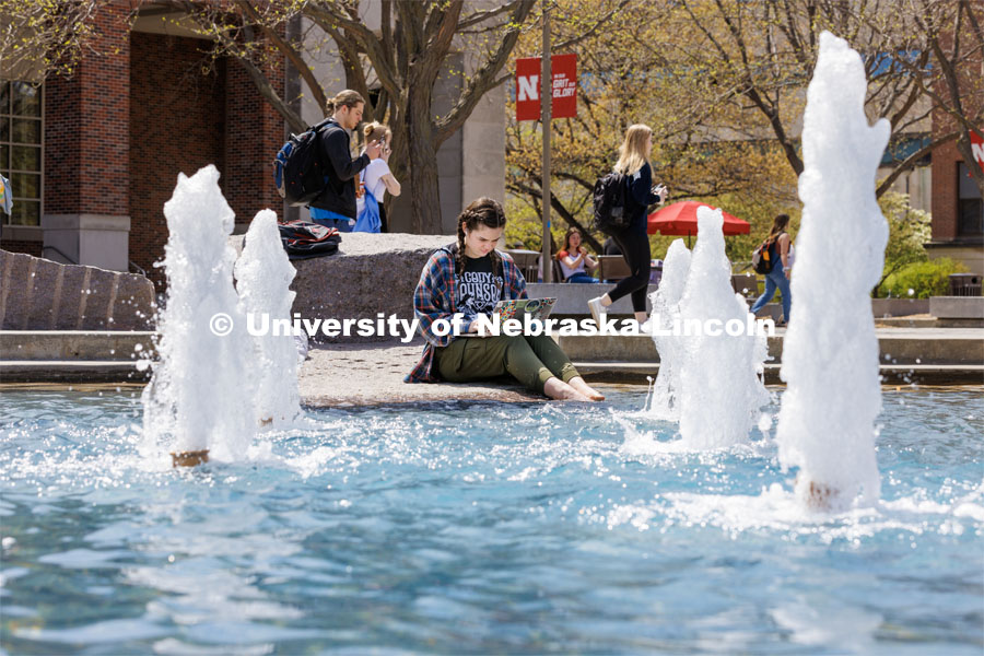 Erin Dodds, a junior from Oak Hills, California, dips her toes in the Broyhill Fountain while studying outside the Nebraska Union. Spring on City Campus. April 18, 2023. Photo by Craig Chandler / University Communication.