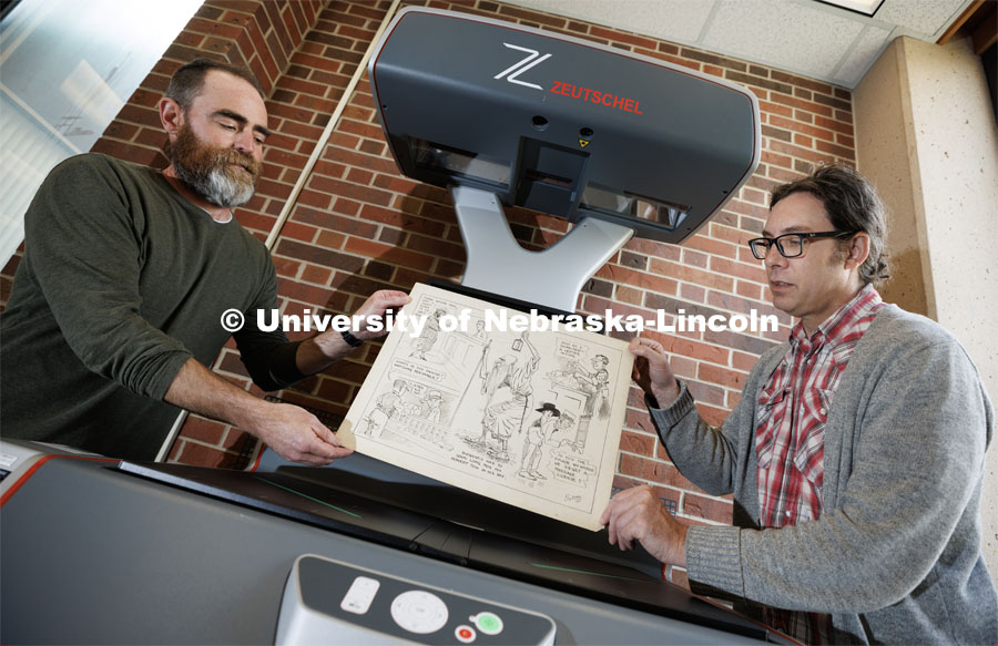 Richard Graham (right), Associate Professor in University Libraries, and John Wiese place an Oz Black cartoon onto the scanner bed to digitize the drawing. Graham and Wiese are building an online archive of editorial cartoons from Nebraska alumnus Oz Black. These cartoons are mostly from the 1920s and 1930s and ran in Nebraska newspapers headquartered in Lincoln. April 20, 2023. Photo by Craig Chandler / University Communication.