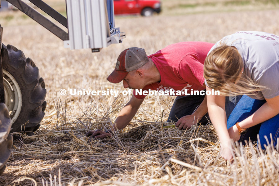 Graduate student Ian Tempelmeyer, left, and graduate research assistant Taylor Cross dig through the dirt to check for seed planting depth and spacing. The self-driving robotic planter based on Santosh Pitla’s tractor platform works its way through a field at the Rogers Memorial Farm east of Lincoln. April 27, 2023. Photo by Craig Chandler / University Communication.