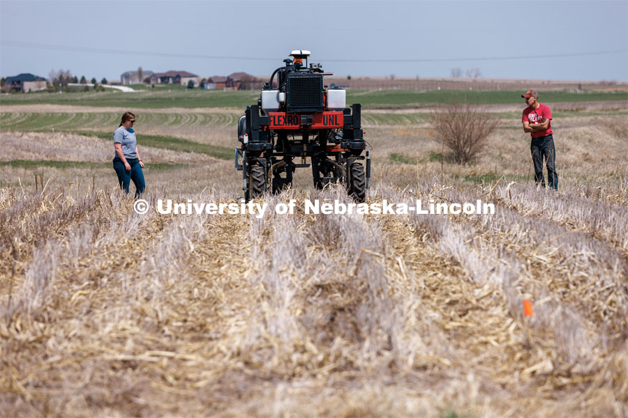 Graduate research assistant Taylor Cross (left) and graduate student Ian Tempelmeyer walk behind the Flex-Ro autonomous planting robot as it starts a row at Rogers Memorial Farm, east of Lincoln. Santosh Pitla, associate professor of advanced machinery systems at Nebraska, has managed the project since the robot’s inception in 2015. April 27, 2023. Photo by Craig Chandler / University Communication.