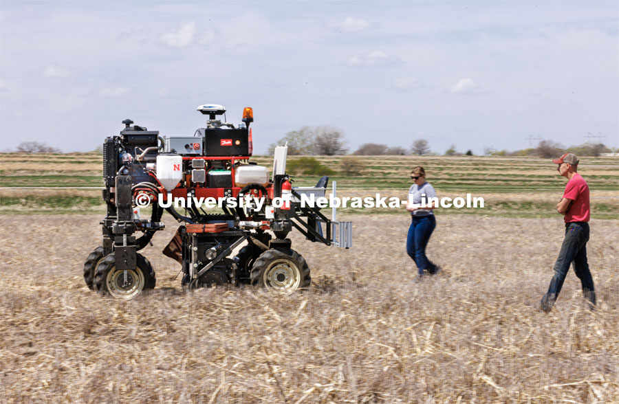 Graduate student Ian Tempelmeyer, right, and graduate research assistant Taylor Cross walk behind the Flex-Ro autonomous planting robot as it starts a row. The self-driving robotic planter based on Santosh Pitla’s tractor platform works its way through a field at the Rogers Memorial Farm east of Lincoln. April 27, 2023. Photo by Craig Chandler / University Communication.