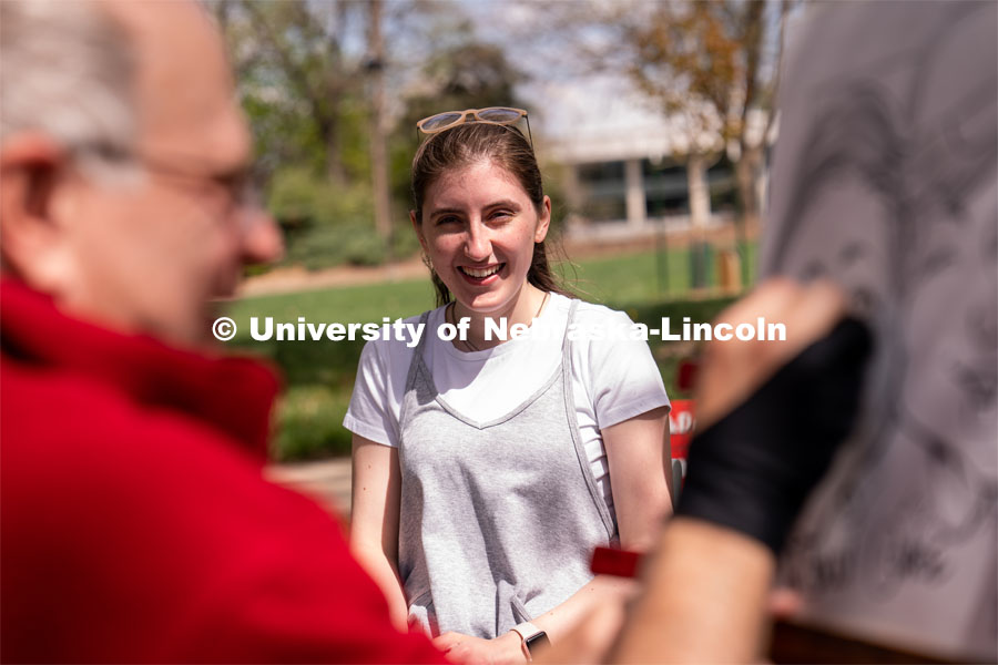Junior Human Development and Family Sciences major Molly Storm laughs as a caricature of her is drawn at the 2023 End of Year Bash at East Campus Mall. April 29, 2023. Photo by Jordan Opp for University Communication.