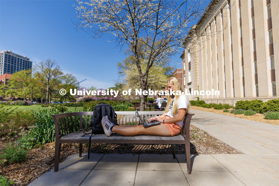 Izzy Knutson, a sophomore from Lincoln, sits outside Love Library working on her laptop. May 4, 2023. Photo by Craig Chandler / University Communication.