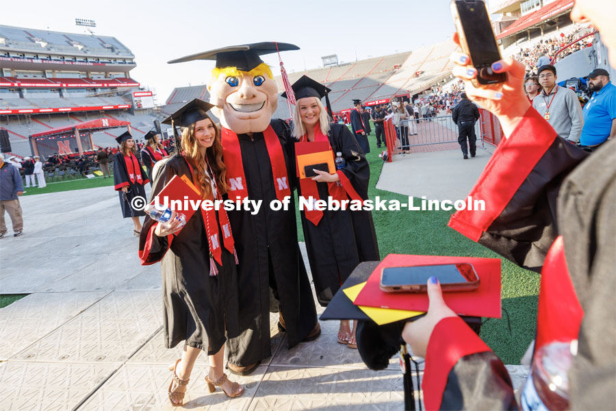 Herbie Husker poses with graduates Saturday. Undergraduate commencement at Memorial Stadium. May 20, 2023. Photo by Craig Chandler / University Communication.