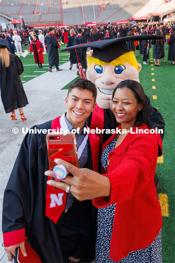 Husker Cheer Squad member Logan Larsen, cheer coach Erynn Butzke and Herbie Husker pose for a selfie before the ceremony. Undergraduate commencement at Memorial Stadium. May 20, 2023. Photo by Craig Chandler / University Communication.