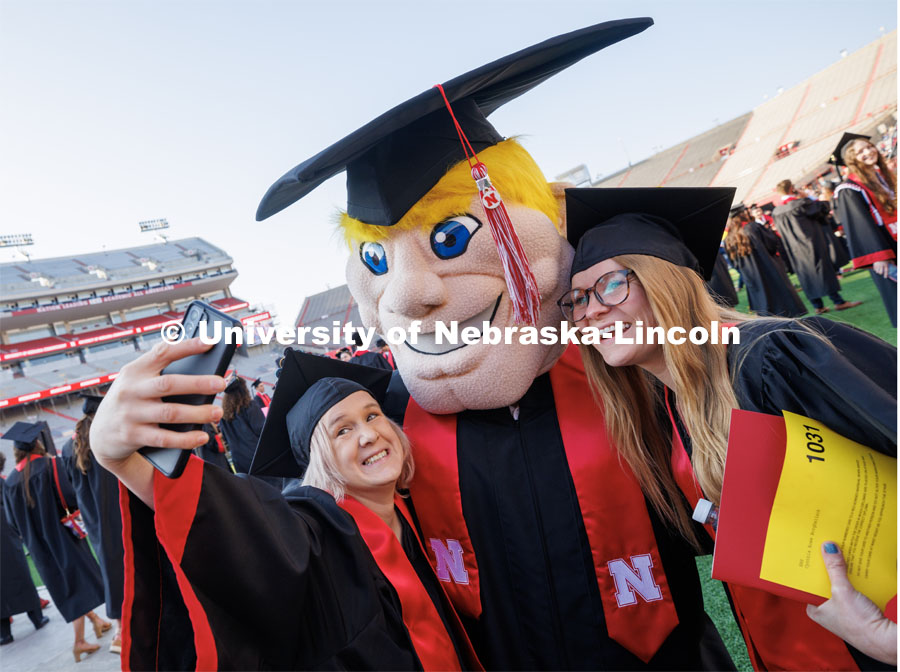 Jeanetta Goc and Cynthia Borgheiinck take a selfie with Herbie Husker. Undergraduate commencement at Memorial Stadium. May 20, 2023. Photo by Craig Chandler / University Communication.