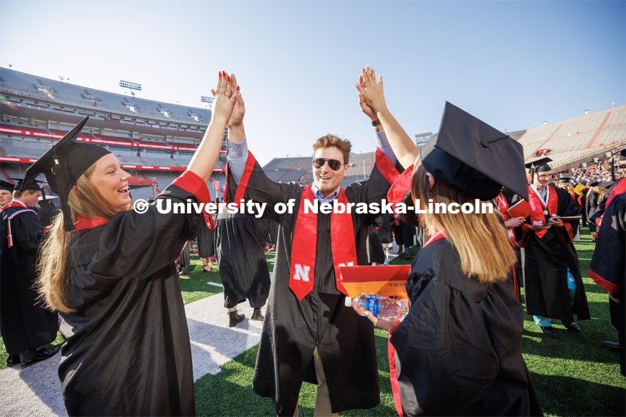 Jenna Ebbers and Erin Witte high-five Walter Fitzsimmons before the ceremony. Undergraduate commencement at Memorial Stadium. May 20, 2023. Photo by Craig Chandler / University Communication.