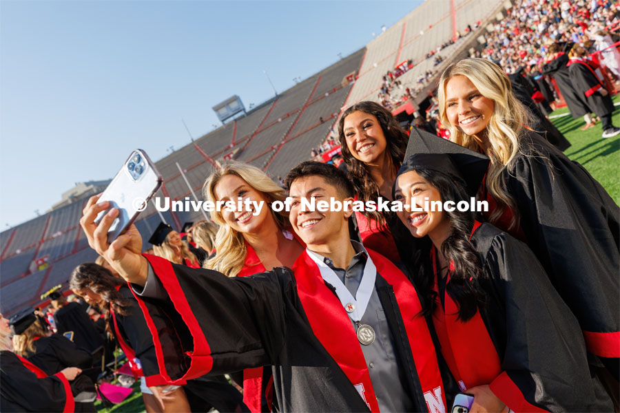 Logan Larsen and other members of the Husker Cheer Squad gather for a selfie before the ceremony. Undergraduate commencement at Memorial Stadium. May 20, 2023. Photo by Craig Chandler / University Communication.