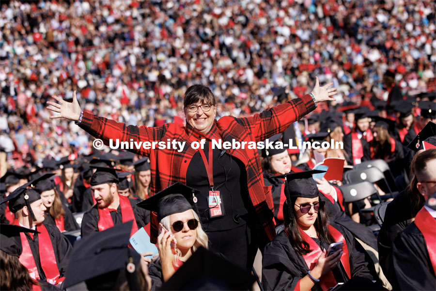 Annette Wetzel, Executive Director, Special Events and Protocol, smiles for a photo with her arms outstretched in a sea of Husker grads before undergraduate commencement. Undergraduate commencement at Memorial Stadium. May 20, 2023. Photo by Craig Chandler / University Communication.