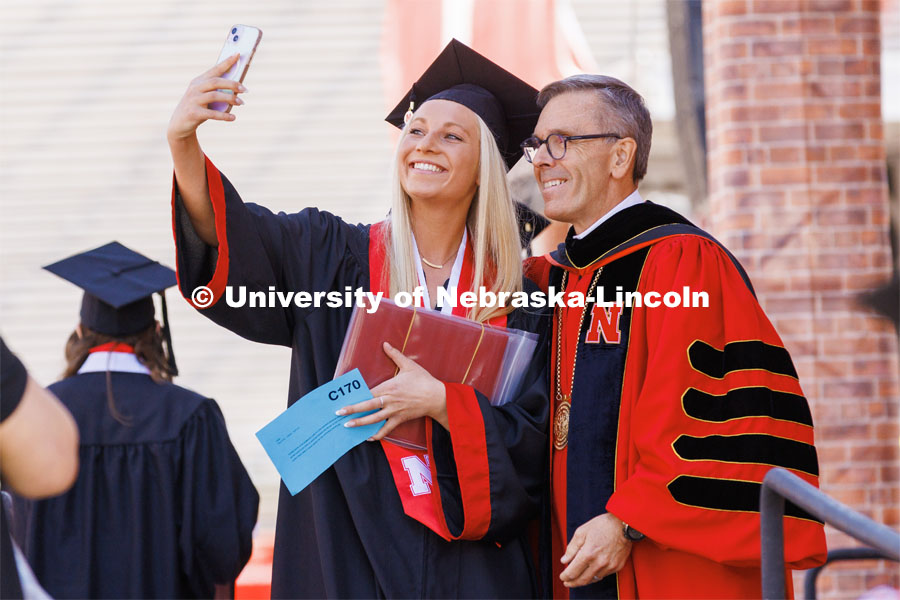 Taylor Peter, a Chancellor Scholar who finished at UNL with a 4.0 GPA, takes a selfie with Chancellor Ronnie Green after she received her diplomas. Undergraduate commencement at Memorial Stadium. May 20, 2023. Photo by Craig Chandler / University Communication.