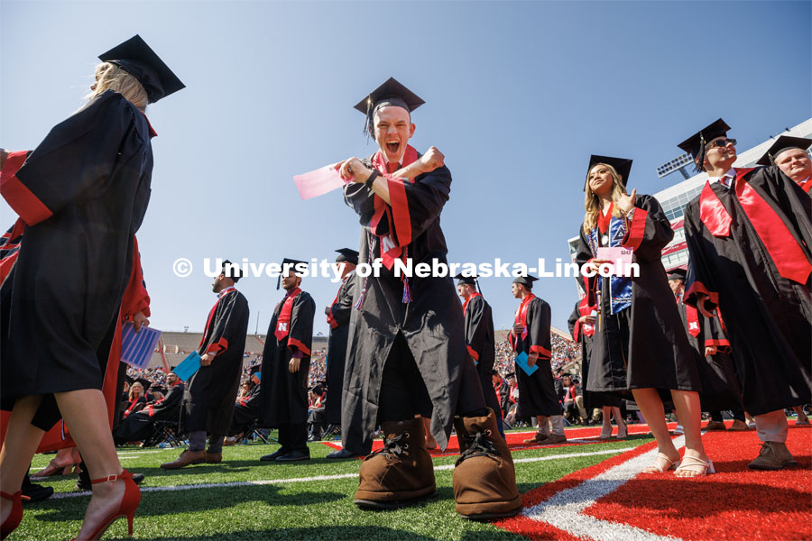 Brendan Kauth-Fisher, a graduate in business administration, throws the bones while waiting to receive his diploma. Brendan has been seen by thousands the past three years performing as Herbie Husker. Herbies are allowed to reveal themselves at commencement by wearing Herbie’s shoes to walk. Undergraduate commencement at Memorial Stadium. May 20, 2023. Photo by Craig Chandler / University Communication.