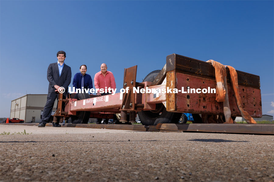 From left: Cody Stolle, Josh Steelman and Ron Faller lean against a sled connected to a ground anchor. The sled will be pulled to at a high speed to test the strength of the anchor for stopping it. Cody Stolle, Research Assistant Professor and Assistant Director of the Midwest Roadside Safety Facility is leading a group researching better checkpoint barriers to help the Department of Defense. June 5, 2023. Photo by Craig Chandler / University Communication.