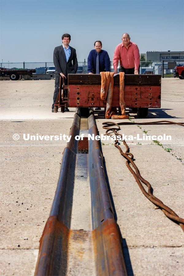 From left: Cody Stolle, Josh Steelman and Ron Faller lean against a sled connected to a ground anchor. The sled will be pulled to at a high speed to test the strength of the anchor for stopping it. Cody Stolle, Research Assistant Professor and Assistant Director of the Midwest Roadside Safety Facility is leading a group researching better checkpoint barriers to help the Department of Defense. Photo used for 2022-2023 Annual Report on Research at Nebraska. June 5, 2023. Photo by Craig Chandler / University Communication.