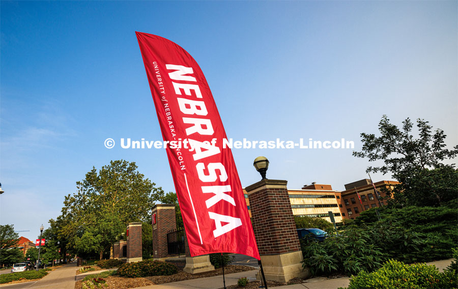 A Nebraska flag welcomes new students near the entrance gates on City Campus. New Student Enrollment. June 16, 2023. Photo by Craig Chandler / University Communication.
