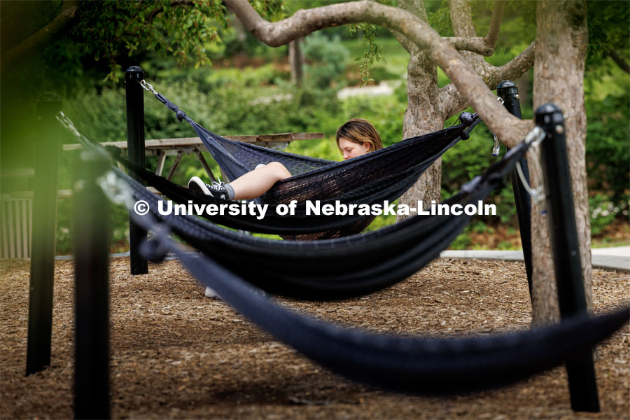 Elsie McCabe, a senior from Omaha, found immediate seating in the hammocks outside the Nebraska Union. Seating will be more limited in a little more than 6 weeks when fall classes begin and the campus fills up again. July 6, 2023. Photo by Craig Chandler / University Communication.