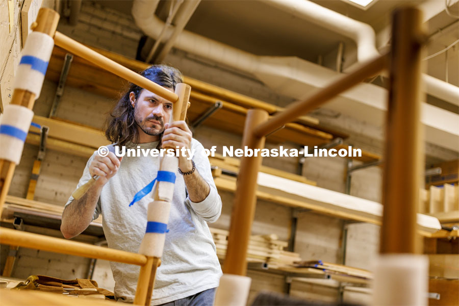 Joeseph Holmes, manager of the Art Fabrication Space in Richards Hall, eyes a piece of furniture he’s constructing from recycled cedar in his studio adjacent to the woodworking shop in the basement of Richards Hall. July 7, 2023. Photo by Craig Chandler / University Communication.