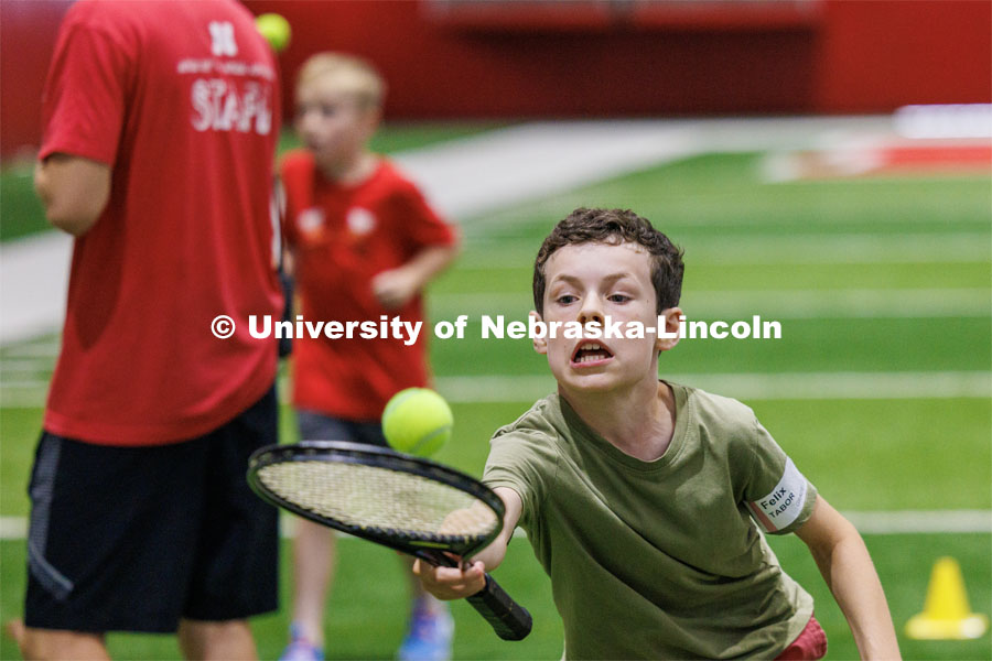 Felix Tabor tries to not let his tennis ball get away from him in the tennis relay. Campers had to bounce a ball on their racquet walking backwards and forwards. Husker Kids Camp. July 25, 2023.  Photo by Craig Chandler / University Communication.