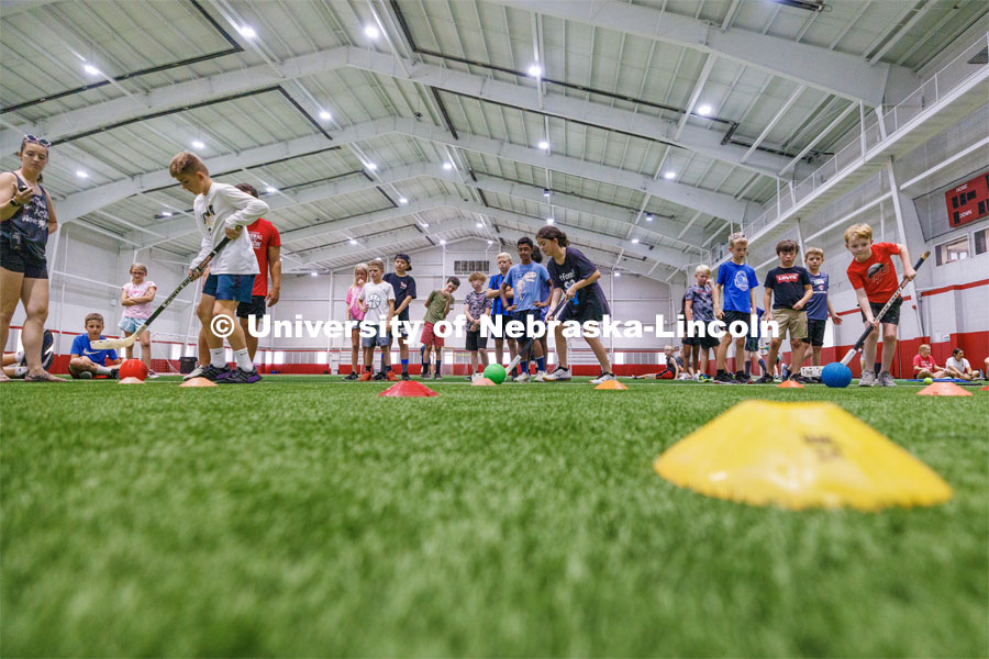 Campers in a field hockey relay where they had to maneuver the ball around cones. Husker Kids Camp. July 25, 2023.  Photo by Craig Chandler / University Communication.