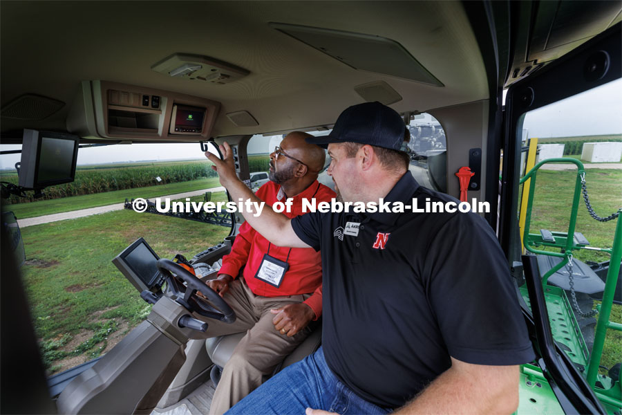 Chancellor Rodney Bennett rides in the cab of a John Deere 612R self-propelled spraying rig as Quentin Cooksley, Director of Commercial and Application Business at AKRS Equipment and UNL alumni, describes the computer system that uses cameras and computers to only spray the weeds. The sprayer was being demonstrated at the South Central Ag Lab field day for area farmers. IANR Roads Scholar Tour through Nebraska. August 1, 2023. Photo by Craig Chandler / University Communication.