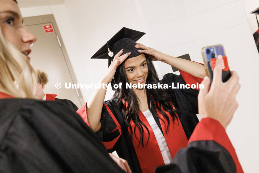 Jazmine Graham uses her friend’s phone as a mirror to adjust her mortar board. The University of Nebraska–Lincoln is conferring 588 degrees during the combined graduate and undergraduate commencement ceremony at Pinnacle Bank Arena. August 12, 2023. Photo by Craig Chandler/ University Communication.