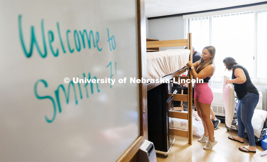 Carmela VanZyl fixes the corner of her mattress pad as she moves into her Smith Residence Hall room with the help of her parents, Maria and Peter. Sunday early arrival move-in for sorority rush. August 13, 2023. Photo by Craig Chandler / University Communication.