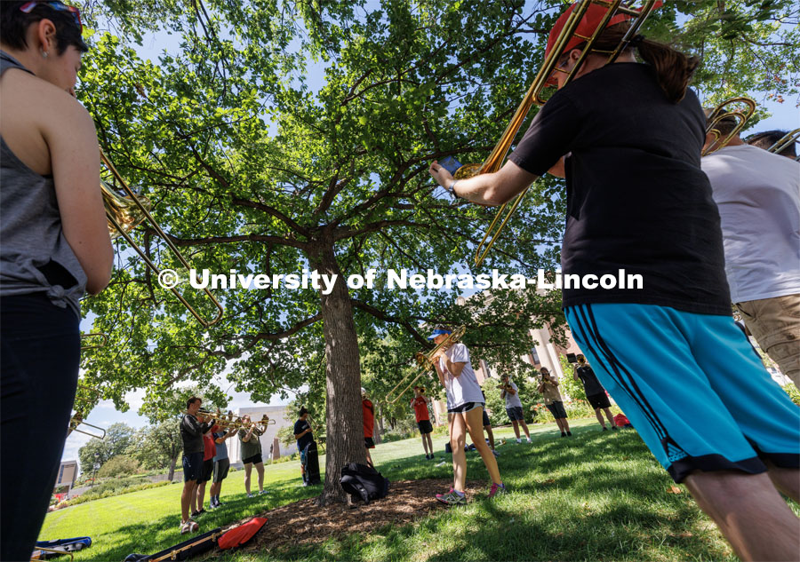 Janelle Johnson of Lincoln leads the trombone section while practicing in the shade of a tree in front of Pound Hall. Cornhusker Marching Band camp practice. August 14, 2023. Photo by Craig Chandler/ University Communication.