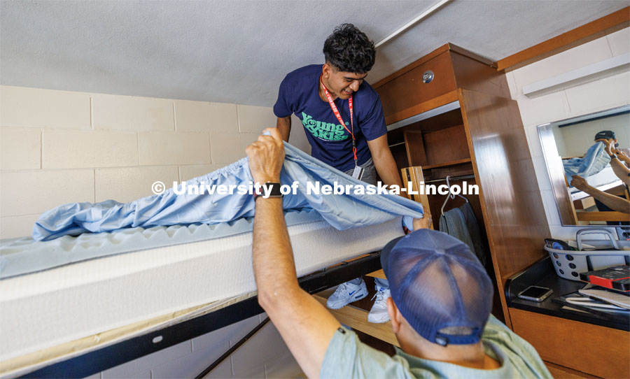 Jose Lopez of Gibbon works on making his bed with help of his dad, Jose, and his sister, Stephanie (in mirror). Jose is majoring in Sports Media in the CoJMC. First day of residence hall move-in. August 14, 2023. Photo by Craig Chandler/ University Communication.