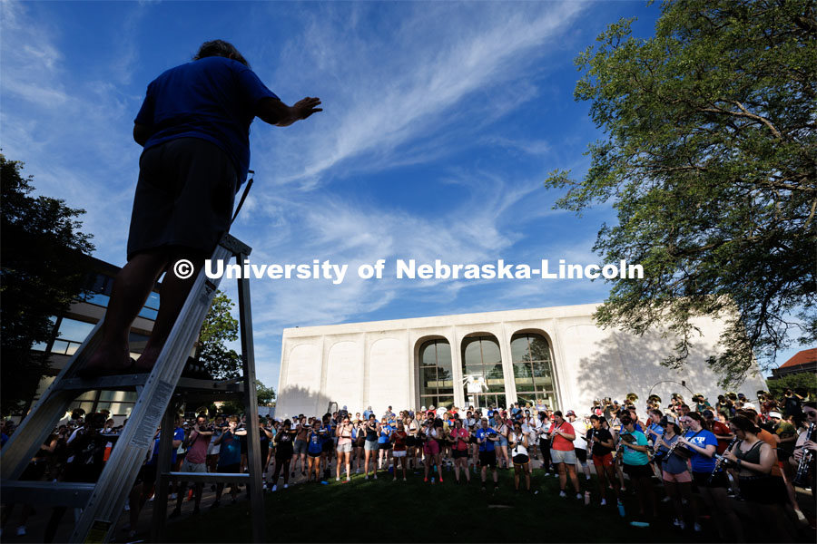 Tony Falcone directs the band practice. The band practices on the greenspace by the Sheldon Art Museum as their normal pregame concert area next to the Kimball Recital Hall is under construction. Cornhusker Marching Band practice. August 16, 2023. Photo by Craig Chandler/ University Communication.