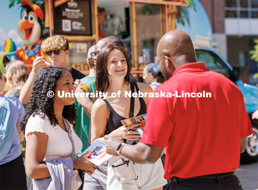 Aida Burks, left, from Lincoln, and Hailey Hall, from Omaha, talk with Nicholas Gordon, a College of Arts and Sciences recruiter, at the college welcome. Student kickoffs by colleges to welcome new and returning students. August 17, 2023. Photo by Craig Chandler / University Communication.