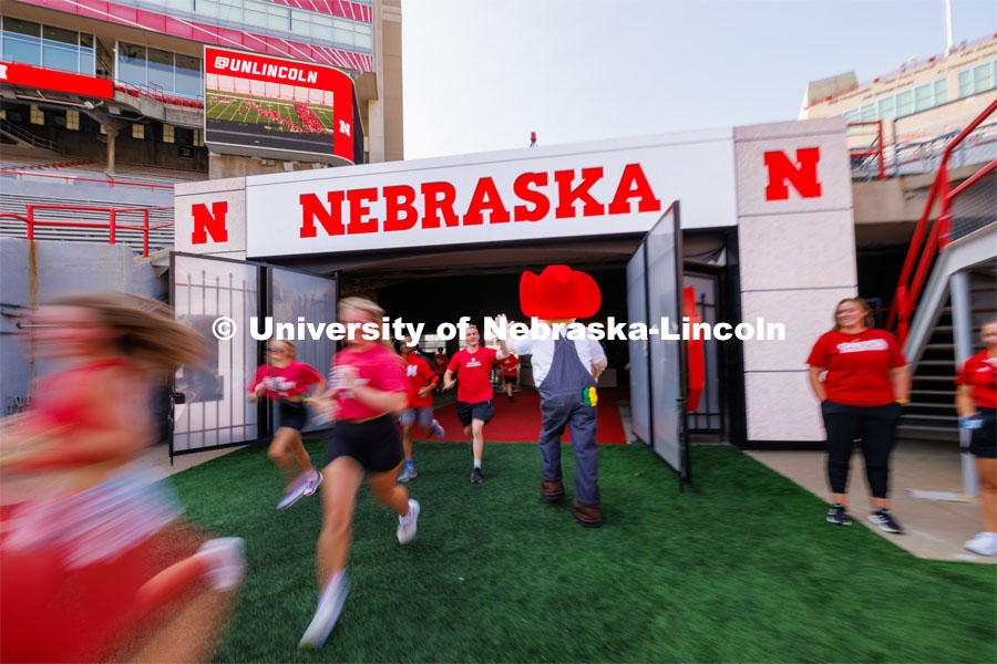 Students high five Herbie Husker as they charge out of the gates at the Tunnel Walk. Tunnel Walk in Memorial Stadium. August 18, 2023. Photo by Craig Chandler / University Communication.
