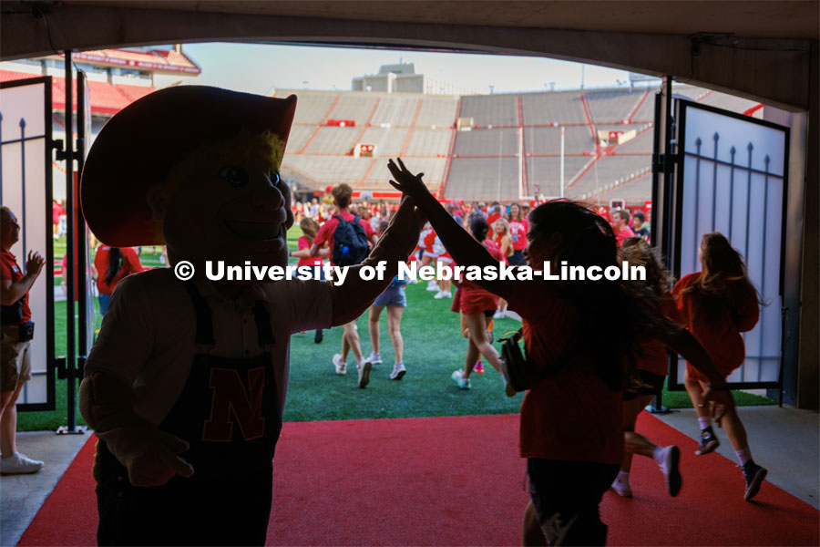 Students high five Herbie Husker as they charge out of the gates at the Tunnel Walk. Tunnel Walk in Memorial Stadium. August 18, 2023. Photo by Craig Chandler / University Communication.