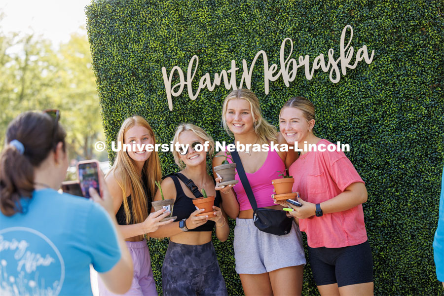 Freshman Anna Clarke from Waverly, Sydney Misiunas from Papillion and Brooke Thorstenson and Alexis Gross, both from Sioux Falls, South Dakota, have their picture taken at the Plant Nebraska booth. Wellness Fest in front of the Nebraska Union and on the green space. August 19, 2023. Photo by Craig Chandler / University Communication.
